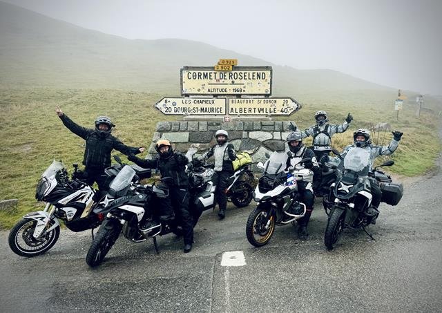 Gruppe von Motorradfahrern mit BMW R 1250 GS am Cormet de Roselend in den Alpen, umgeben von Nebel und Bergen.