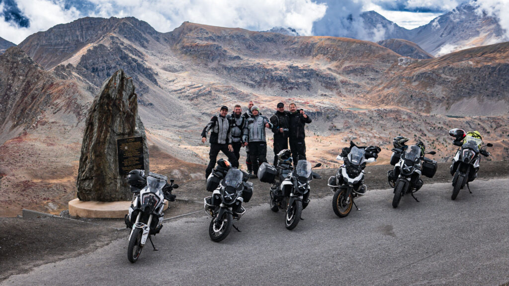 Group of motorcyclists in front of an impressive Alpine backdrop with several BMW and KTM motorcycles, ideal for motorcycle tours in the mountains.