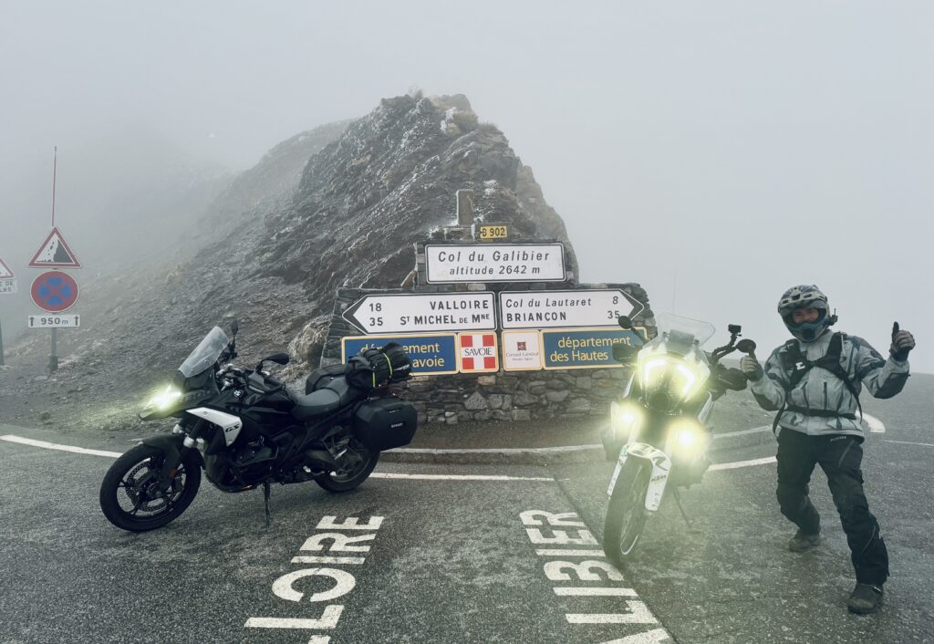 Motorcyclists with BMW and KTM bikes at the Col du Galibier at an altitude of 2642 meters in foggy weather - perfect motorcycle tour through the French Alps.