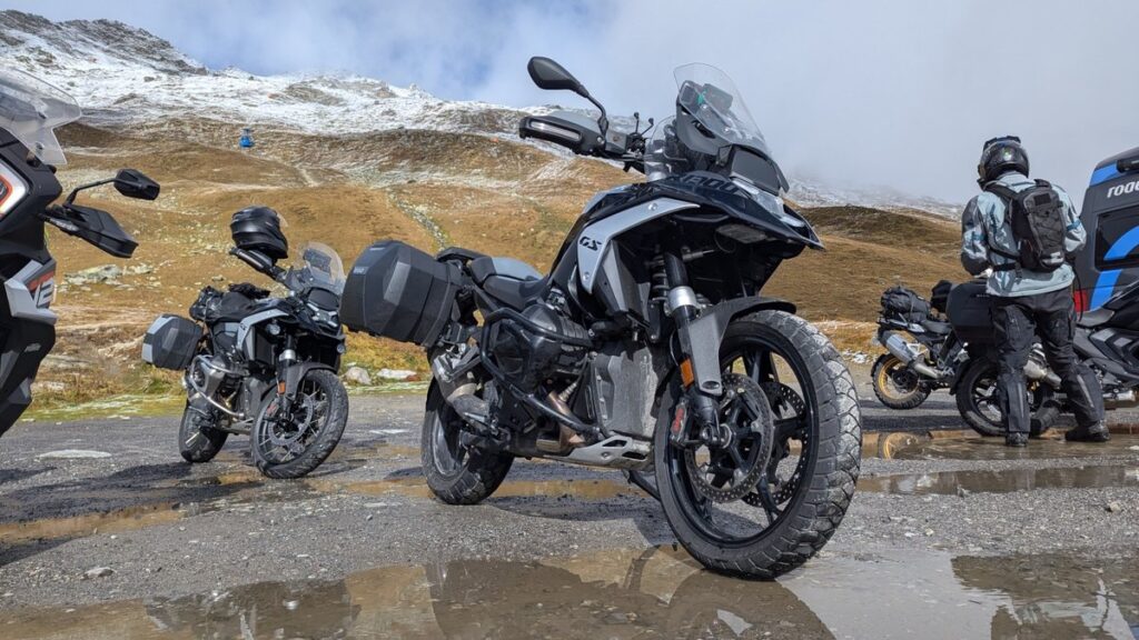 BMW R 1300 GS mit Koffern und Helm vor einem atemberaubenden Bergpanorama.