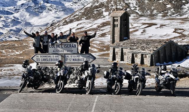 Group of motorcyclists in front of the Col de l'Iseran, the highest asphalted mountain pass in Europe, with an impressive Alpine backdrop - the ideal stop for adventure tours on two wheels.