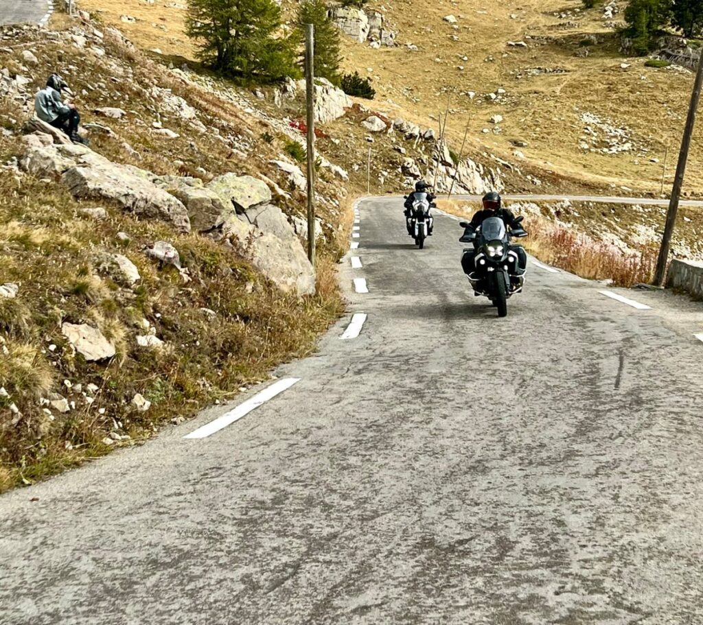 Motocicleta BMW R 1300 GS em uma estrada alpina sinuosa, perfeita para viagens de turismo e aventura.