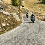 Moto BMW R 1300 GS en una sinuosa carretera alpina, perfecta para viajes de turismo y aventura.