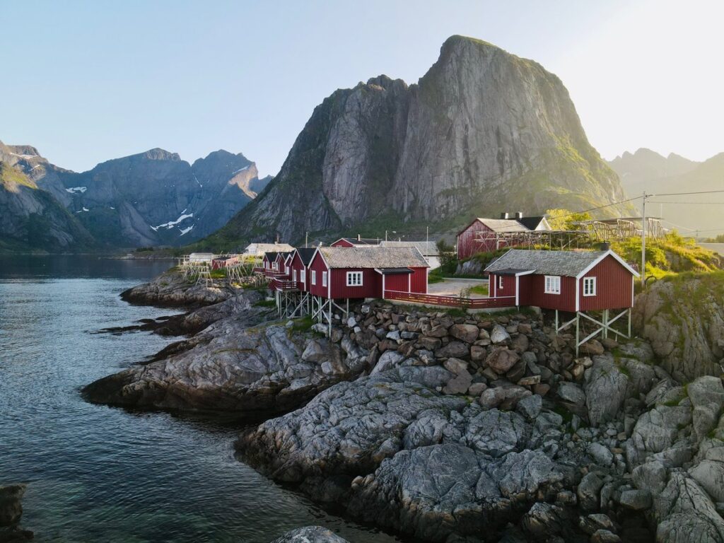 Traditional red fishermen's huts on the Lofoten Islands, surrounded by dramatic mountain scenery - perfect for motorcycle tours.